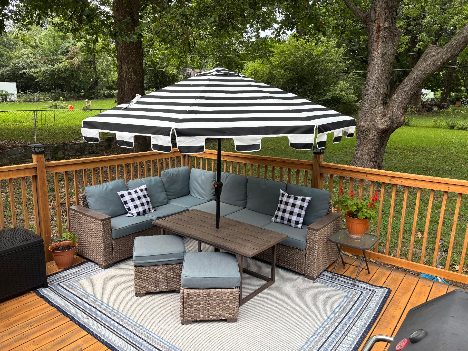 Restored backyard deck with clean warm wood, patio sectional, rug and striped umbrella